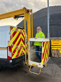 Eilidh is standing on a Hydraulic lift which is raised to the height of a street lighting column to access the lights