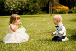 Young children sitting on the grass blowing bubbles