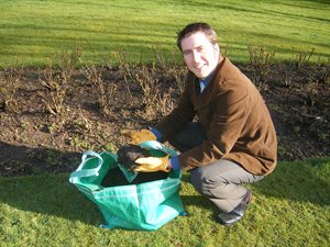Person crouching on the grass with hands lifting out fresh soil from a compost sack