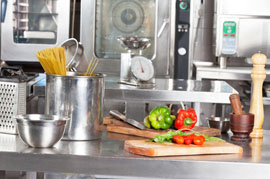 A spotless kitchen in business premises with utensils and peppers on a chopping board