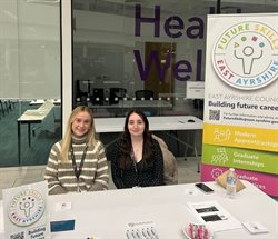 Two young girls sitting at an information desk representing the Future Skills team at a recruitment event