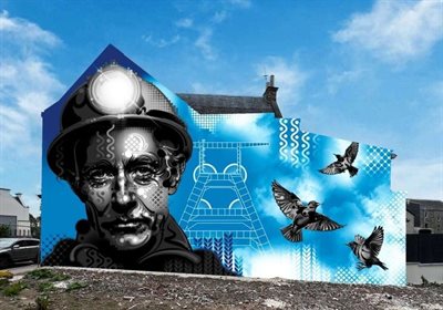 Mural of a miner, winding wheels, mining tools, black diamonds and soaring starlings