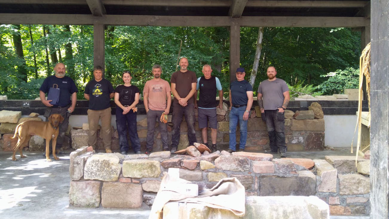 A group of people learning to build a traditional rubble wall and re-pointing