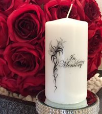 White remembrance candle sitting against a red background of roses