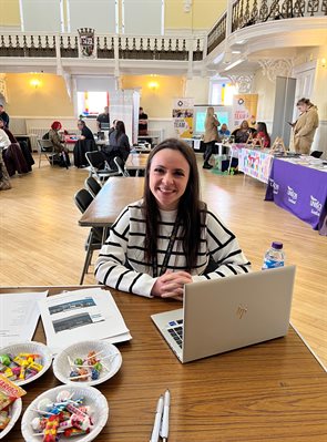 Mackenzie sitting at a table with a laptop at a recruitment event