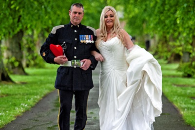 Bride and groom smiling, standing in an avenue of trees