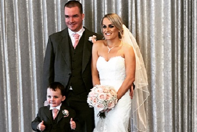 Bride and groom smiling with a little boy in front