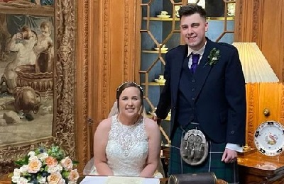 Bride sitting and groom standing at a table, smiling