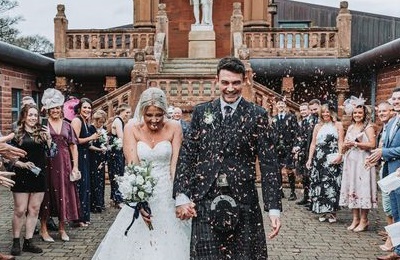 A smiling bride and groom with guests throwing confetti