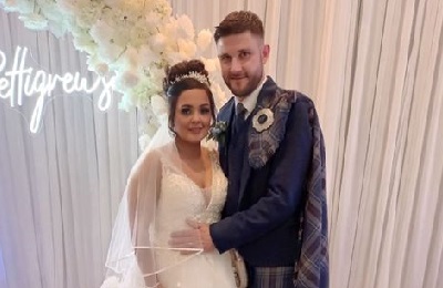 Bride and groom smiling, white curtain and flowers in the background