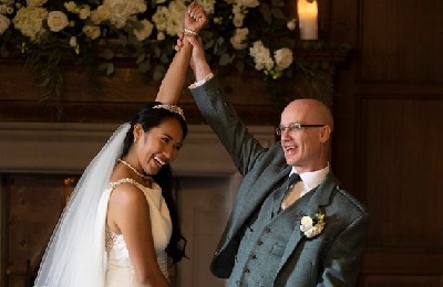 Bride and groom smiling with arms joined up in the air