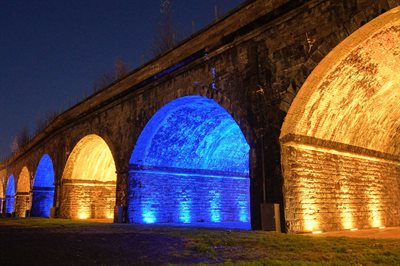 Railway viaduct with arches lit up in alternate yellow and blue