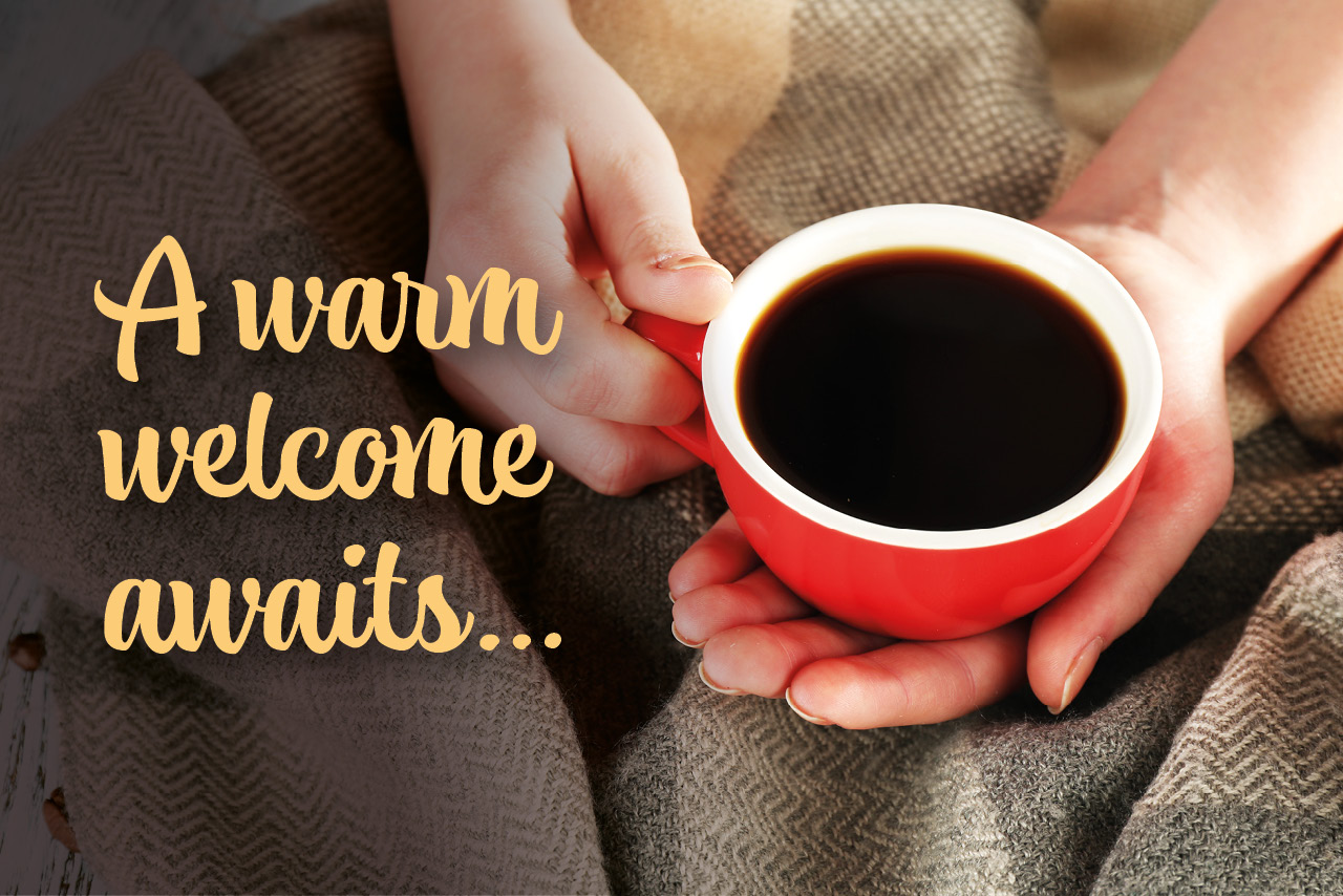 Hands holding a warm drink representing a warm welcome in warm spaces