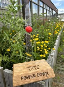 Windy trophy - a windmill character standing on a wooden stand with the words "Winner 2024 - Power Down"